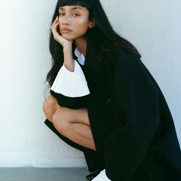 A woman with black jacket and white ruffled shirt 