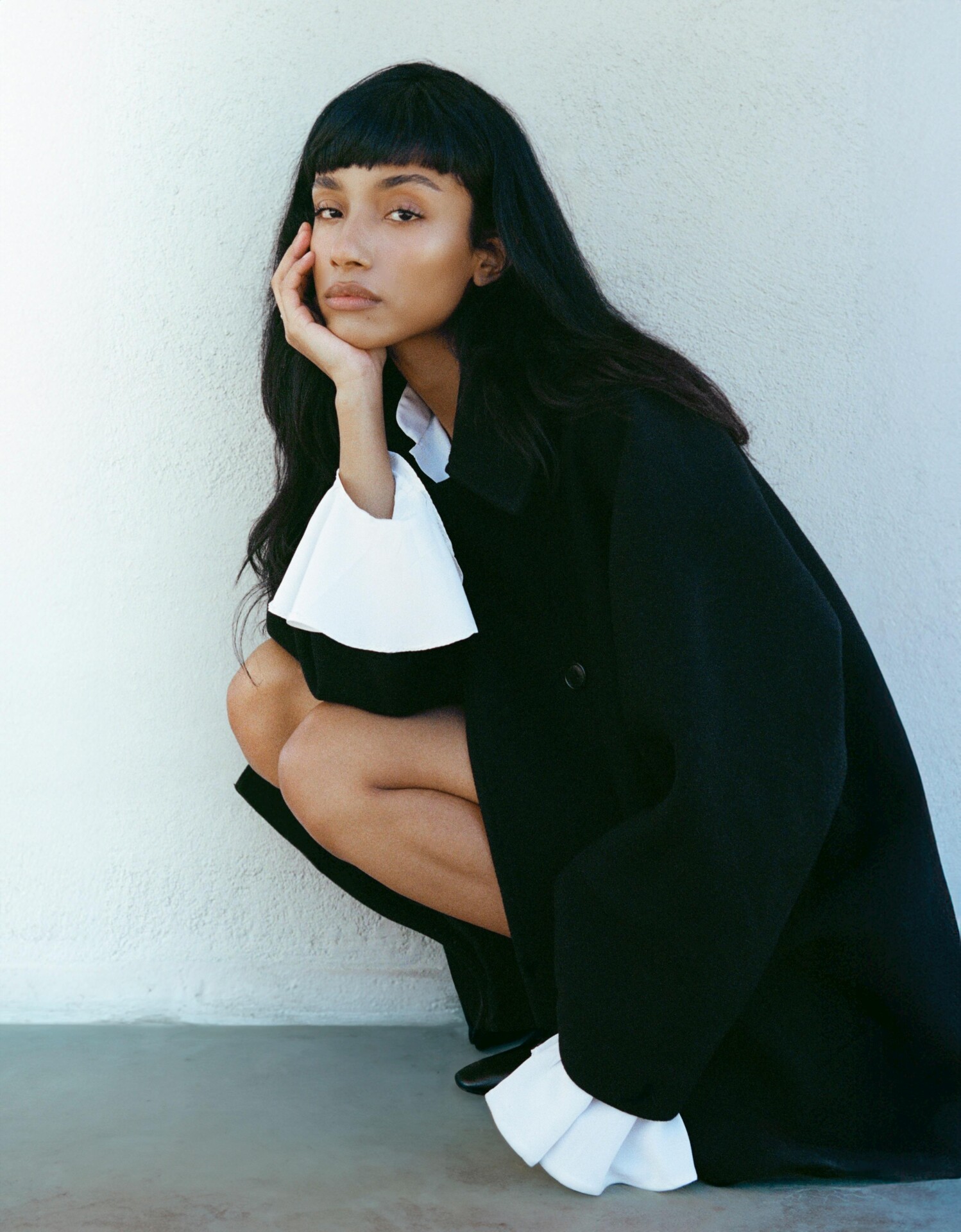 A woman with black jacket and white ruffled shirt 