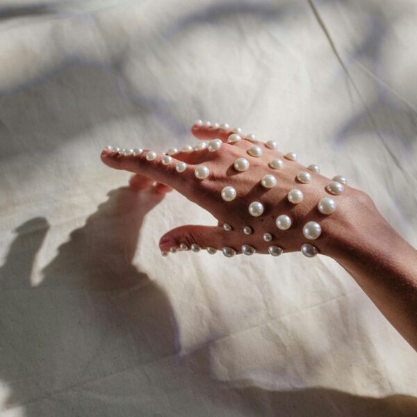 Hand with white pearls on natural fabric
